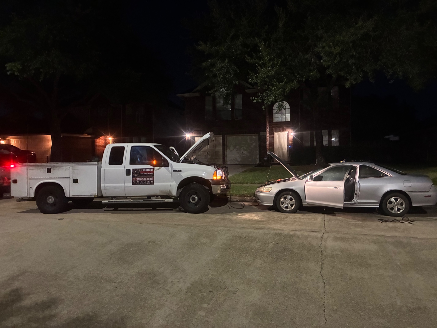Freedom Mobile Repair service truck jump-starting a Honda Accord at night