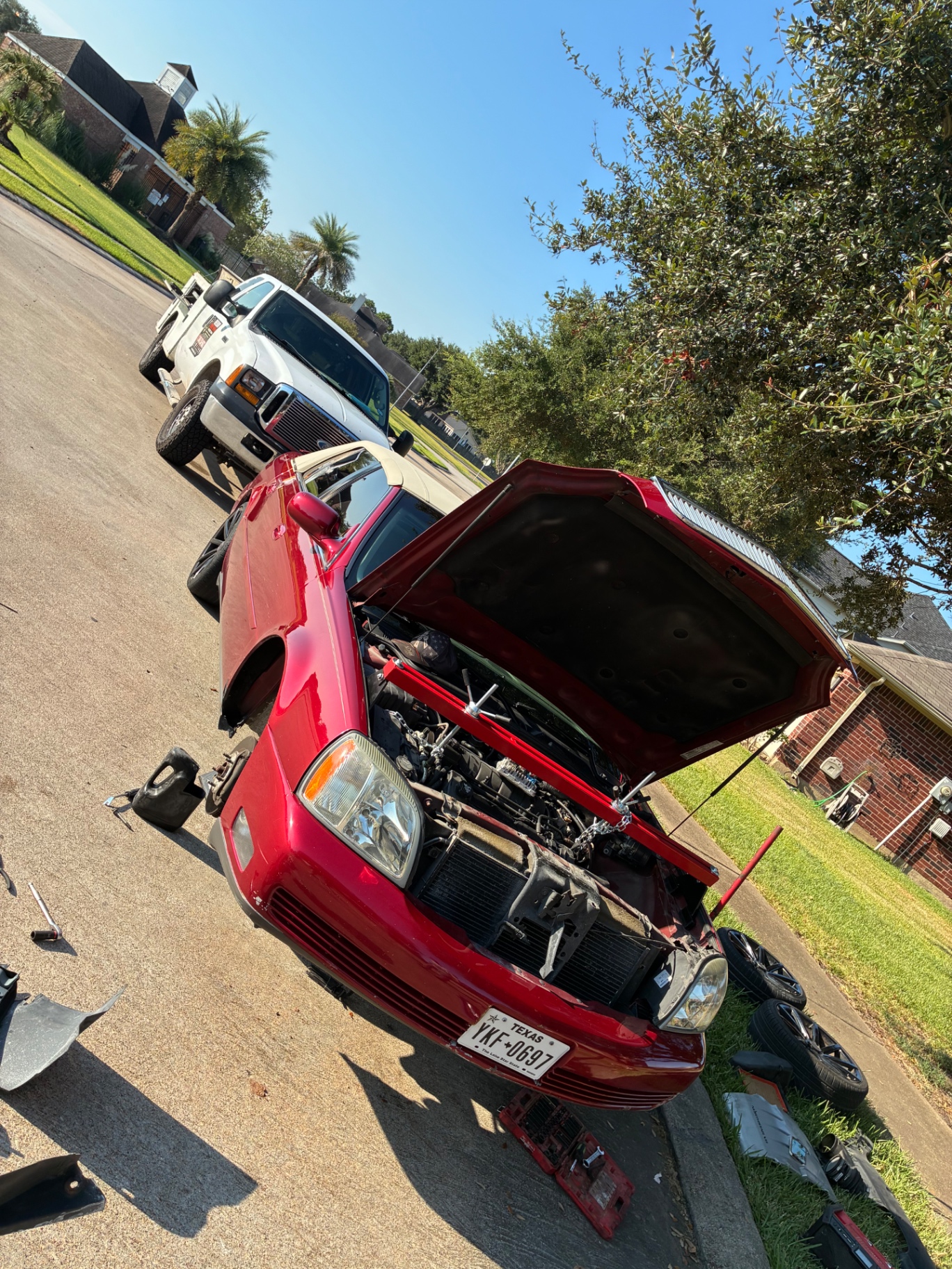 Cadillac with the hood up and front end apart on a street call