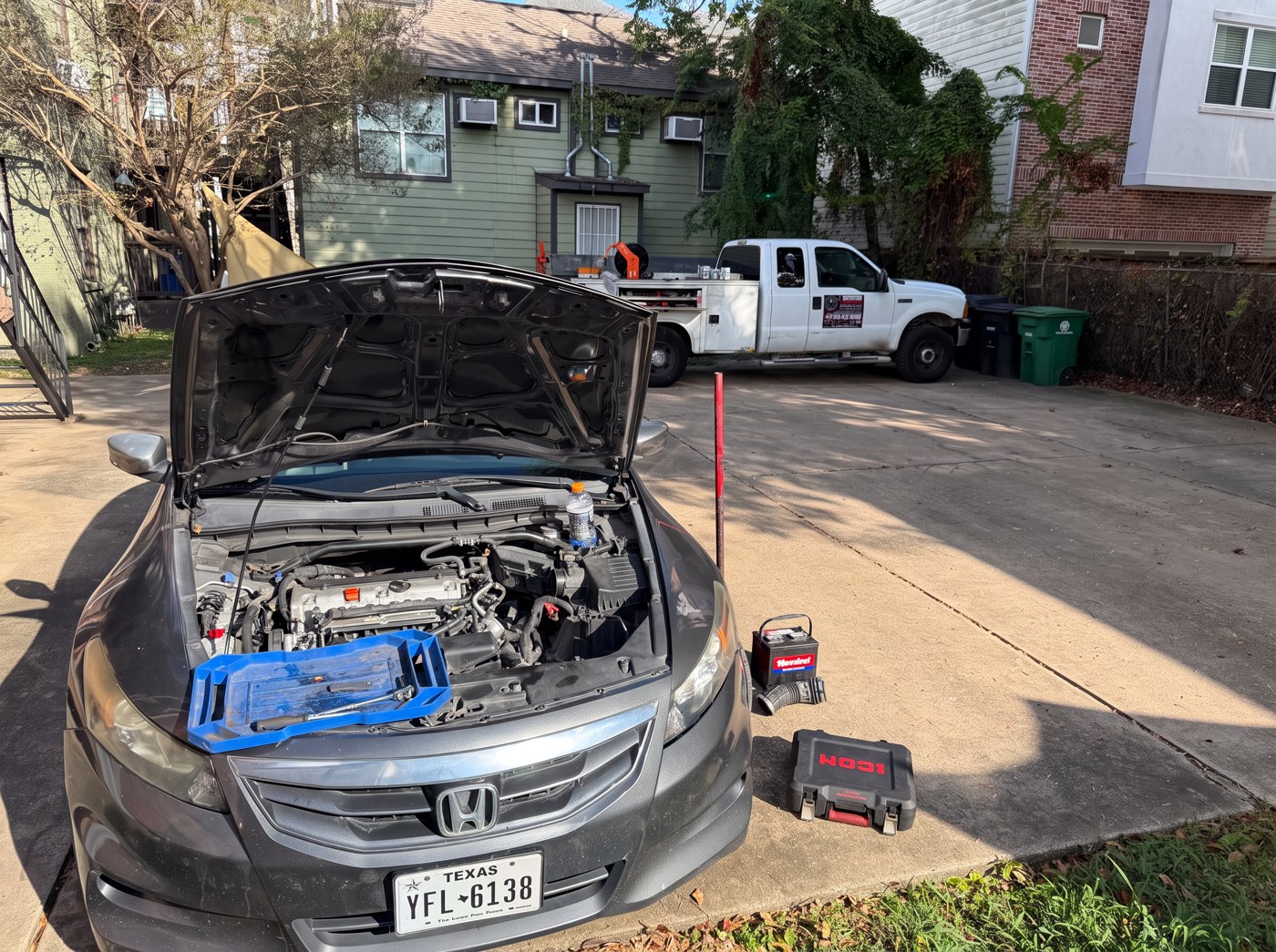 Honda with its hood raised and tools beside the engine, with the Freedom service truck in the background